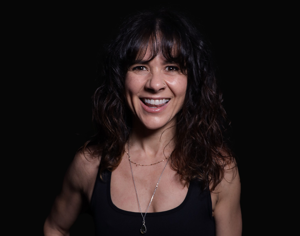 Psycle instructor Ash wearing a black top against a black background