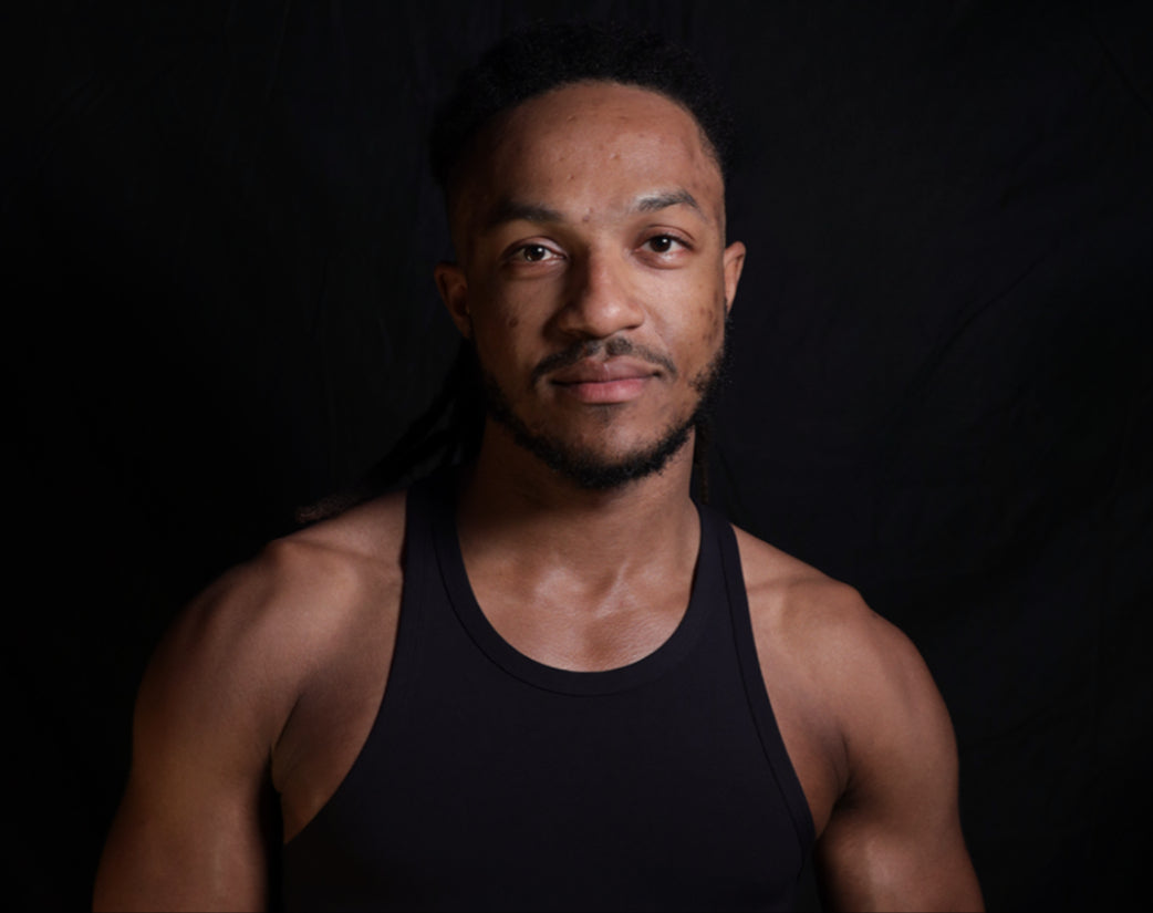 Psycle coach Darius wearing a black tank top against a dark background