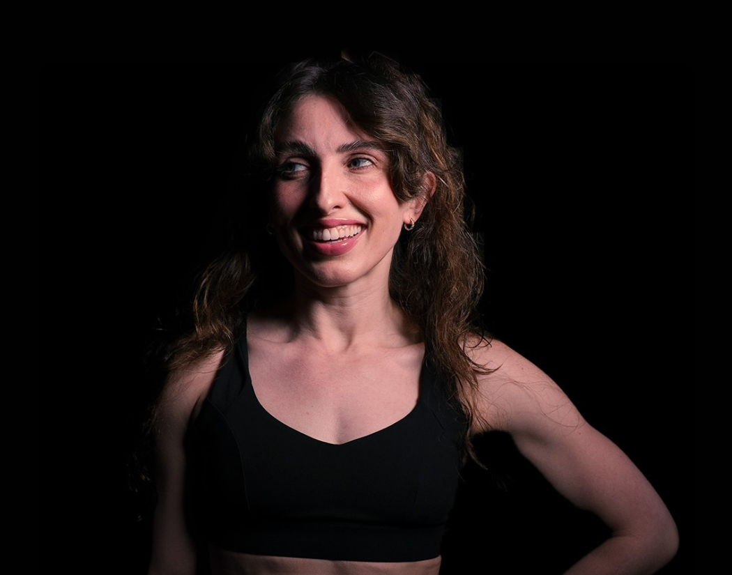 Psycle coach Lisa wearing a black sports bra against a dark background