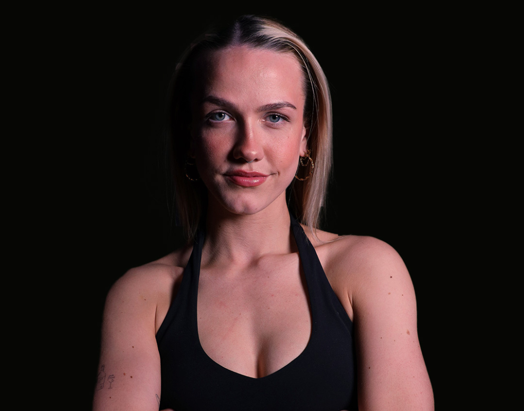Psycle coach Maria J wearing a black tank top against a dark background