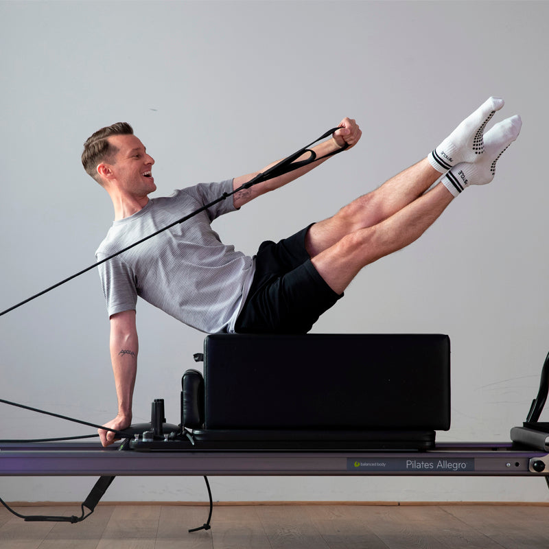 Reformer instructor Ben leaning backwards on Reformer block