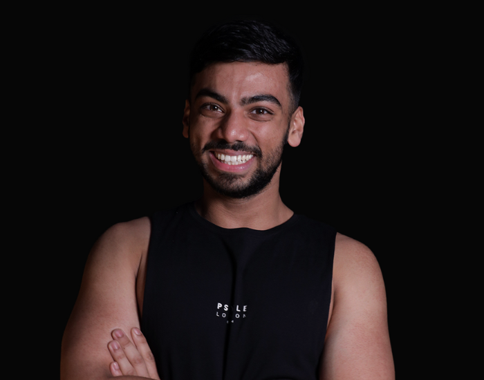 Riazul wearing a black sleeveless shirt with text on a dark background
